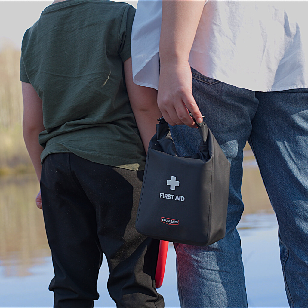 Housegard Waterproof första hjälpen-väska i miljöbild, svart och kompakt, idealisk för utomhusaktiviteter.